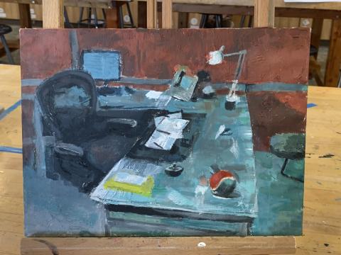 A painting depicts a cluttered office desk with various items. The desk has a computer monitor, an open book, papers, a lamp, and a red and white ball. The background shows an empty chair and shelves with additional items.