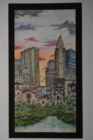 A detailed watercolor painting of a cityscape at sunset. The artwork features a mix of historic and modern buildings, including a prominent skyscraper with an ornate spire. The sky is painted with hues of orange, pink, and purple, reflecting the setting sun.