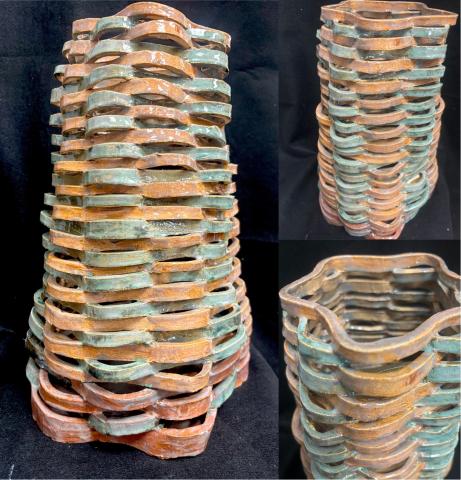 A ceramic vase with a unique, wavy, and layered design. The vase features alternating bands of earthy brown and turquoise colors