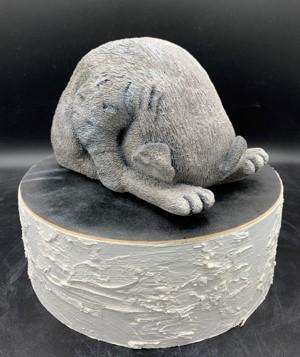 Clay ceramics creation of a young white kitty in a head downward position on a small white round pedastal