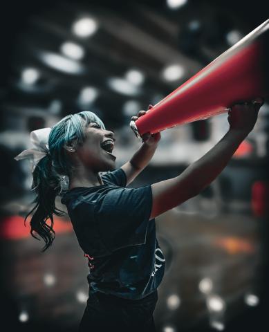 Photograph of a Davis Cheerleader motivating the fans with a cheerful smile and energetic personality.