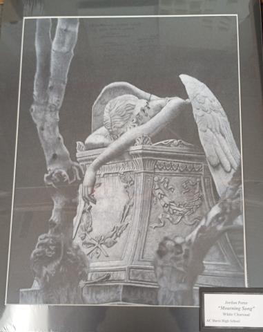 A grave with a gothic architectural theme. An angel draped over grave in a resting position. Arms covered in cracks. Eerie atmosphere. Contrast form the black base and white charcoal.