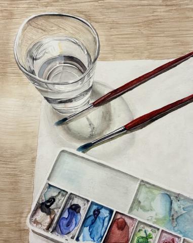 A semi-realistic watercolor portraying painting tools. A glass cup with water, two red paintbrushes, a clearly used paint palette, and a paper towel lay on a desk as if placed without thought.