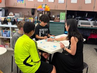 A group of students and their teacher doing math at a table.