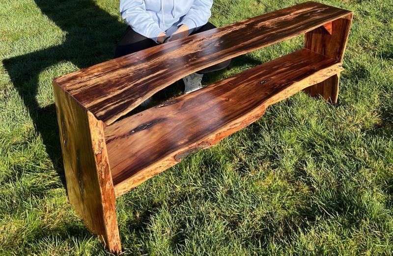 A wooden bench with a rustic design. The bench is made from slabs of wood with visible grain patterns and knots. It has two levels.