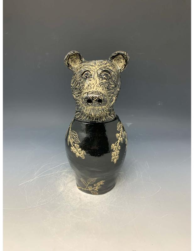 The artwork features a black ceramic vase with a bear's head as the lid. The bear's head is detailed with textured fur and expressive eyes, while the body of the vase showcases delicate golden floral patterns.
