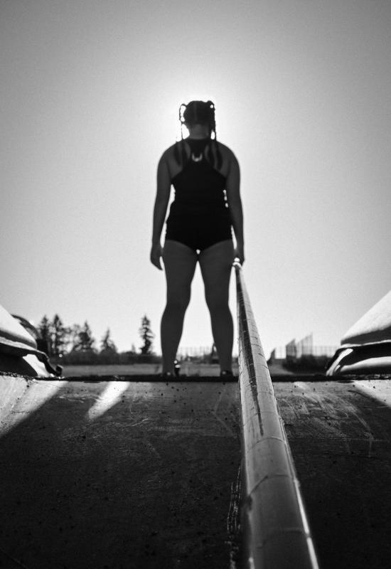 The artwork is a black and white photograph of a person standing at the top of a ramp, facing away from the camera. The person is wearing athletic clothing and has braided hair. 