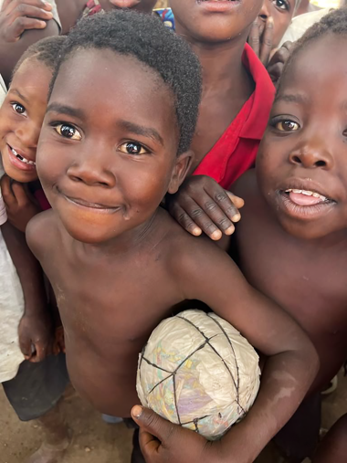A photograph of a group of young boys from Malawi, Africa holding their own soccer ball creation