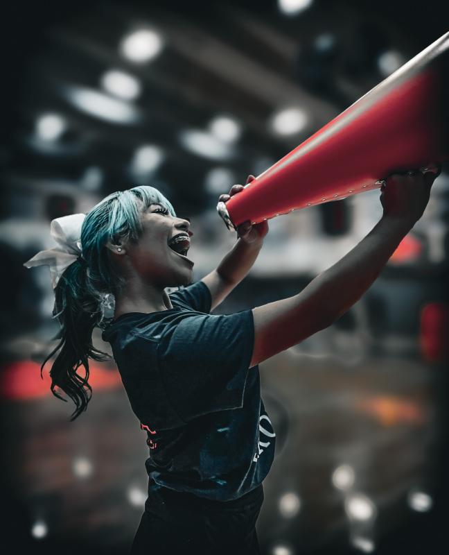 Photograph of a Davis Cheerleader motivating the fans with a cheerful smile and energetic personality.