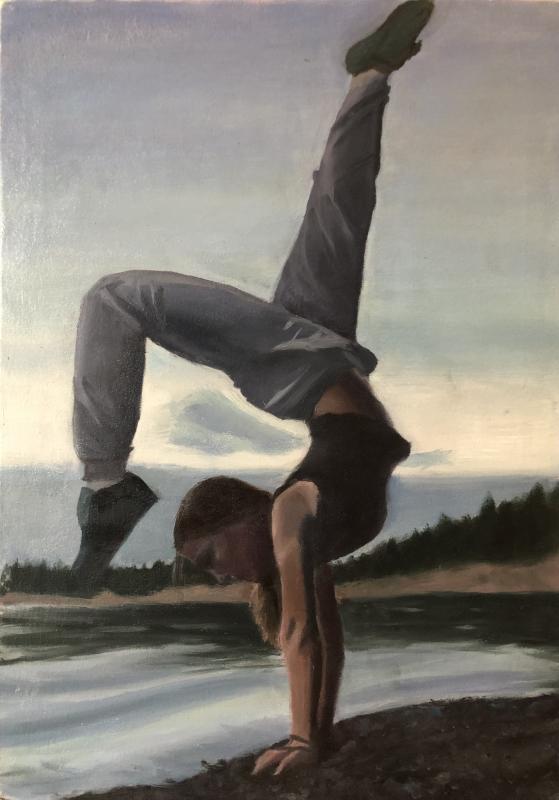 This image shows a shadowy girl in a creative handstand pose, set against the cool-toned landscape of a beach reflecting a vibrant blue sky and forested horizon.
