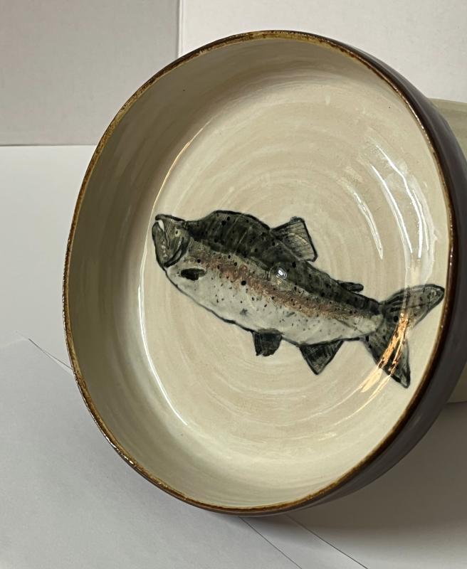 A circular ceramic dish about 2 inches deep and 8 inches wide, with a brown outer edge and white interior that features a pink/humpy salmon