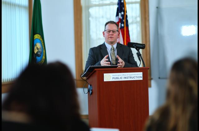 Superintendent Chris Reykdal speaking to the press from a podium at his 2024 Annual K-12 Education Update press conference.