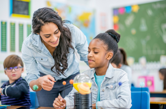 Student and teacher working together in a classroom where learning standards frame what students must know and be able to do at each grade level.