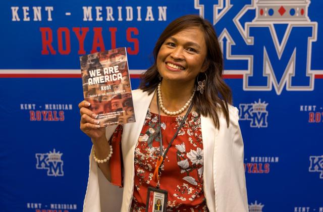 Dr. Marissa Winmill holds up a copy of "We are America: Kent"