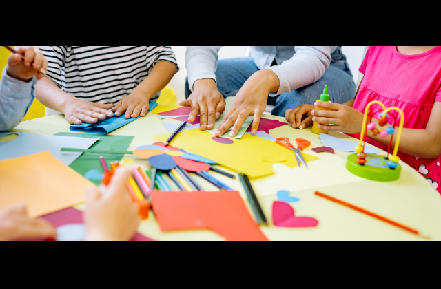 Young students gathered around a table working on projects together.